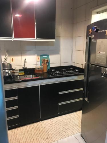 a kitchen with black cabinets and a stove top oven at Quarto para Casal Blumenau in Blumenau