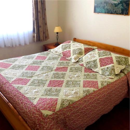 colcha en una cama en un dormitorio con lámpara en Cabañas CentroMontt, en Puerto Montt