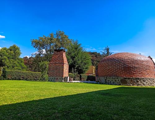 a brick building sitting in a field of grass at Finca Marix, Villa del Carbón in Villa del Carbón