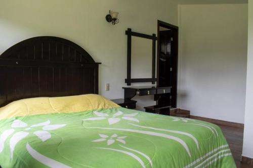 a bedroom with a bed with a green and white blanket at Finca Marix in Villa del Carbón