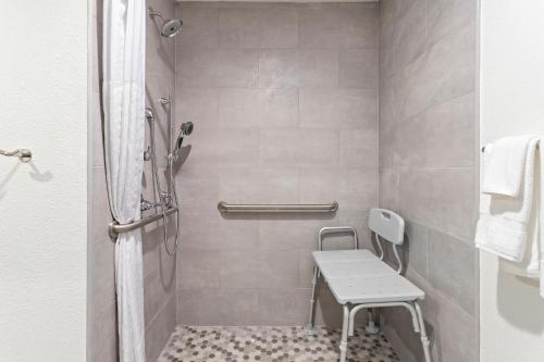 a bathroom with a shower with a bench in it at Hawthorn Extended Stay by Wyndham Port Arthur in Port Arthur