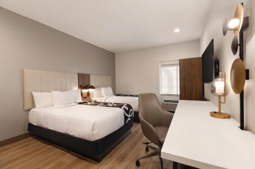 a hotel room with two beds and a desk at Hawthorn Extended Stay by Wyndham Port Arthur in Port Arthur