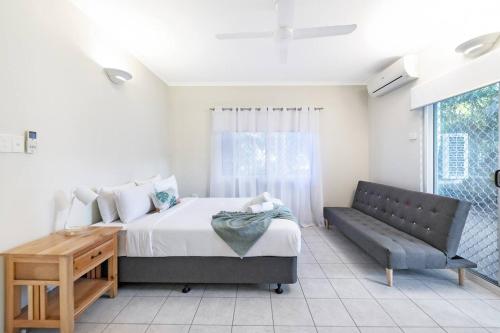 a bedroom with a bed and a couch and a window at Discover a Scandi Style Pool Retreat in Nightcliff in Darwin