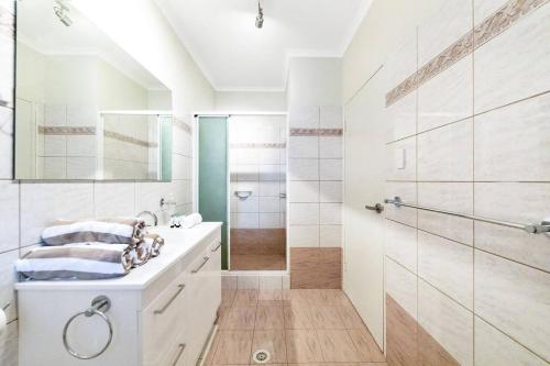 a white bathroom with a shower and a sink at Discover a Scandi Style Pool Retreat in Nightcliff in Darwin