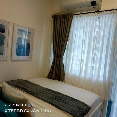 a bedroom with a bed and a window with curtains at Cozy New 1BR Fame Residences Condo with Balcony in Manila