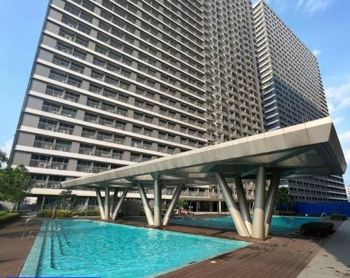 a large building with a swimming pool in front of a building at Cozy New 1BR Fame Residences Condo with Balcony in Manila