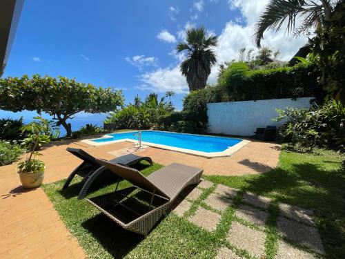 a pool with a lounge chair and a swimming pool at Villa Te Miti in Punaauia
