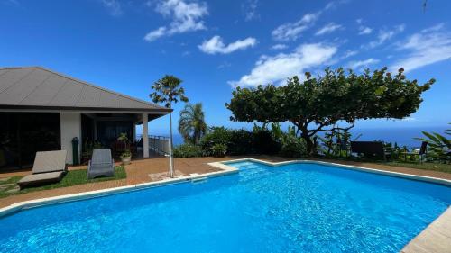 a swimming pool in front of a house at Villa Te Miti in Punaauia