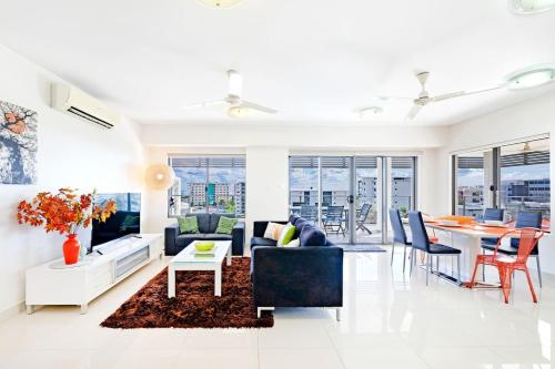 a living room with a couch and a table at 'The Smith' A Vibrant Poolside Balcony Haven in Darwin