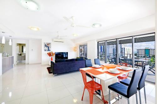 a living room and dining room with a table and chairs at 'The Smith' A Vibrant Poolside Balcony Haven in Darwin