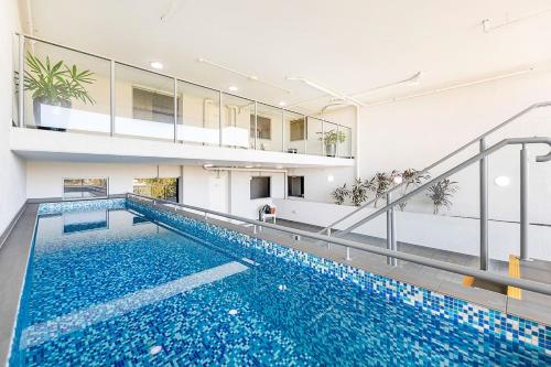 an indoor swimming pool with blue water in a building at 'The Smith' A Vibrant Poolside Balcony Haven in Darwin