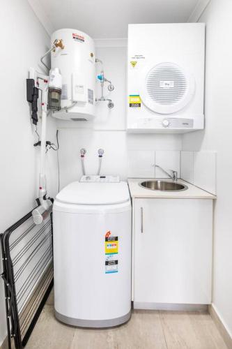 a small kitchen with a sink and a washing machine at 'Top of Town' Resort-style Stay in Heart of Darwin in Darwin