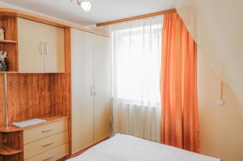 a bedroom with an orange curtain and a window at Фенікс in Yaremche