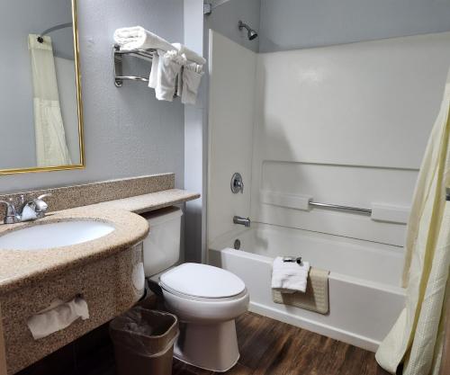 a bathroom with a toilet and a sink and a tub at Desert Inn Tucumcari in Tucumcari