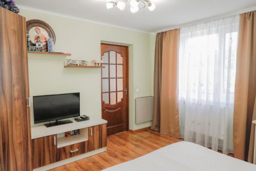 um quarto com uma televisão, uma cama e uma janela em Фенікс em Yaremche