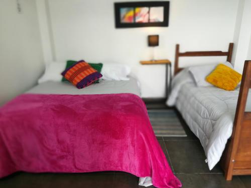 1 dormitorio con 2 camas y manta rosa en Casablanca Choachi, en Choachí