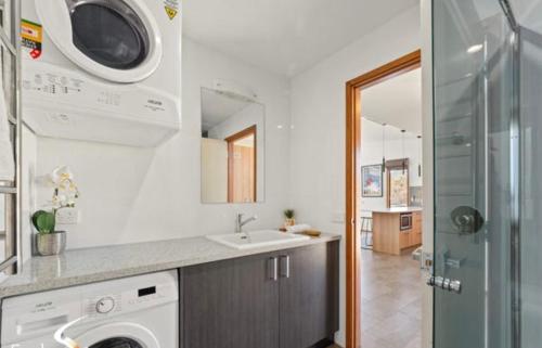 a bathroom with a sink and a washing machine at Lily Chalet in Crackenback