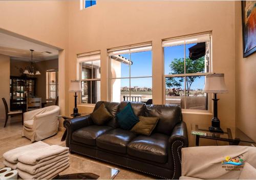 a living room with a leather couch and windows at Come, Experience, Collect memories 24-1 in San Felipe