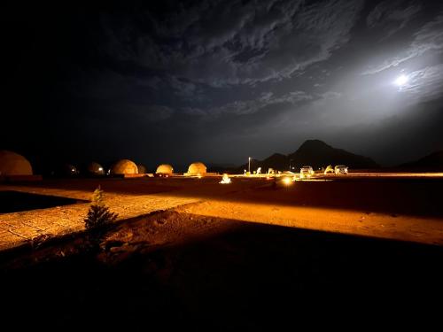 a view of a desert at night with the moon at RUM iSLAND LUXURY CAMP in Wadi Rum