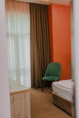 a bedroom with a green chair next to a window at Madina-ZamZam Halal Hotels Group in Baku