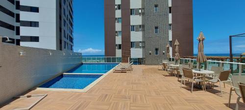 uma varanda de um edifício com piscina, mesas e cadeiras em COPAT0100 - Condomínio Terrazzi Sul Mare em Salvador