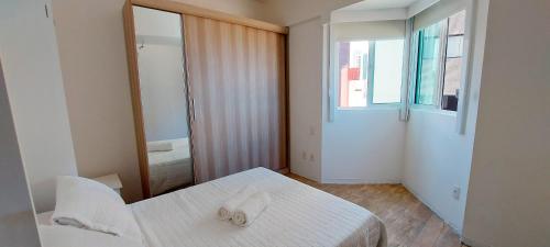 um quarto branco com uma cama e um espelho em COPAT0100 - Condomínio Terrazzi Sul Mare em Salvador