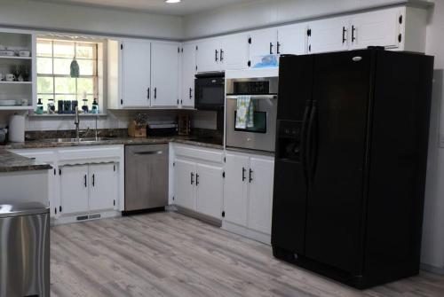 a kitchen with white cabinets and a black refrigerator at Blue Door Farmhouse in Meeker