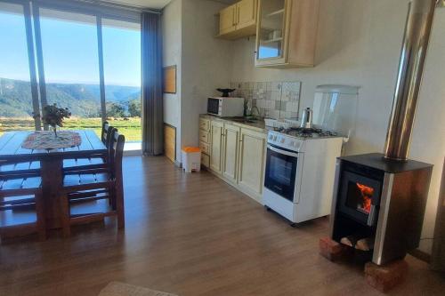 a kitchen with a stove and a table with a view at Alto do morro in Nova Petrópolis