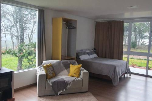 a bedroom with a bed and a couch and a chair at Alto do morro in Nova Petrópolis