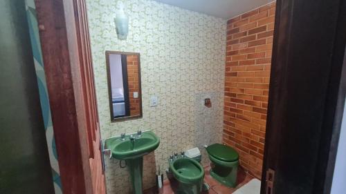 uma casa de banho com 2 WC verdes e um lavatório. em Casa Temporada - Petrópolis/RJ em Petrópolis