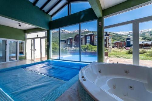 een groot zwembad met een bad en een groot raam bij Catedral Ski & Summer in Bariloche