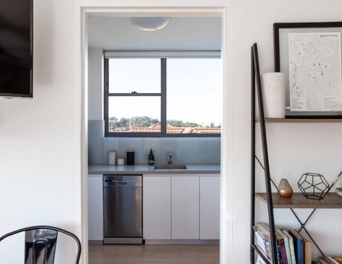 a kitchen with white cabinets and a window at Mosman Bay Magic - Harbourview Studio with Rooftop in Sydney