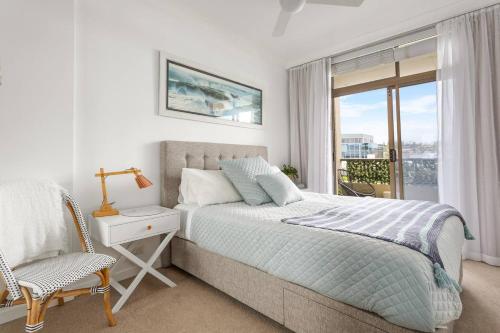 um quarto com uma cama, uma janela e uma cadeira em Fine Pine - Beachside Lifestyle with Two Balconies em Sydney