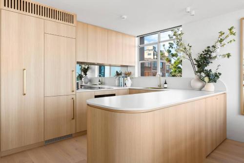 a kitchen with wooden cabinets and a white counter top at Harbour Bliss - Exquisite Design, Breathtaking Views in Sydney