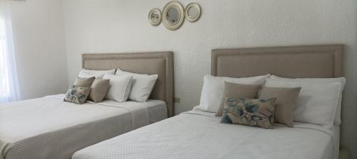2 camas en un dormitorio con 2 relojes en la pared en Apartamentos Manik, en Trujillo