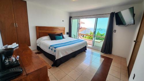 1 dormitorio con cama y ventana grande en Hill House Mazatlan - Bed & Breakfast, en Mazatlán