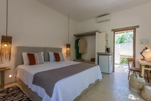 Un dormitorio con una cama grande y una cocina. en Suítes Casa Kamayurá, en Trancoso