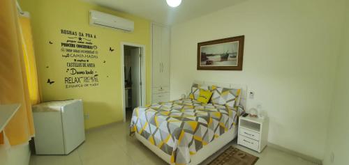 1 dormitorio con 1 cama con edredón amarillo y blanco en Pousada da Drica en Saquarema