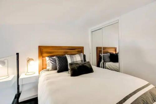 a bedroom with a large white bed and a mirror at Condo moderne, escapade vacance, vue sur montagnes in Mont-Tremblant