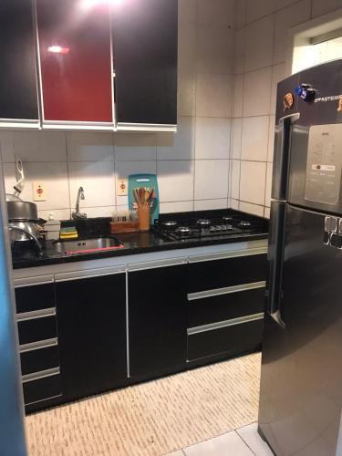 布盧梅瑙的住宿－Quarto para Casal Blumenau，厨房配有黑色柜台、水槽和冰箱。