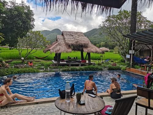 um grupo de pessoas sentadas em torno de uma piscina em um resort em Buzzas @ Pai Chan em Pai