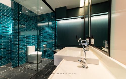 a bathroom with a sink and a toilet and blue tiles at Mercure Miri City Centre in Miri