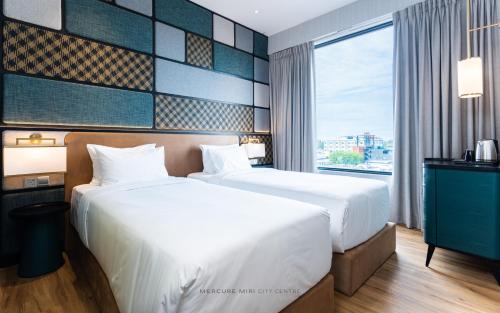 a hotel room with two beds and a window at Mercure Miri City Centre in Miri