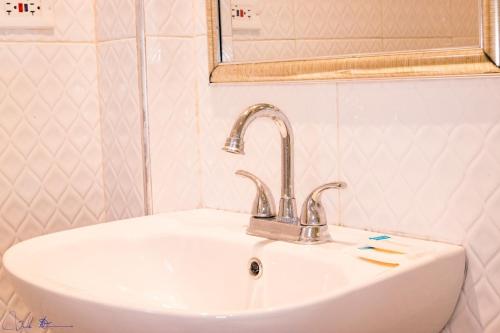lavabo blanco en el baño con espejo en Sunsets at Sunshine Village Lofts, en Negril