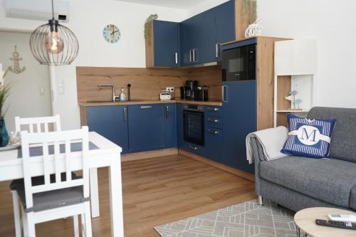 eine Küche und ein Wohnzimmer mit blauen Schränken und einem Sofa in der Unterkunft Strandhaus Döse 1 in Cuxhaven