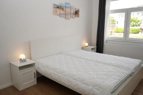 ein weißes Schlafzimmer mit einem Bett und einem Fenster in der Unterkunft Strandhaus Döse 1 in Cuxhaven