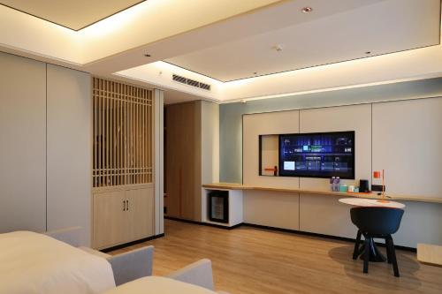 a bedroom with a bed and a tv on the wall at Holiday Inn Express Qingdao Northern West Coast by IHG in Qingdao