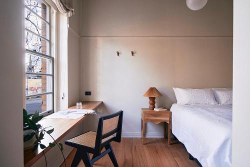 a bedroom with a bed and a desk with a chair at The Courthouse Hotel in Melbourne