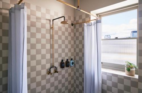 a bathroom with a shower curtain and a window at The Courthouse Hotel in Melbourne