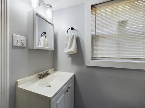 a white bathroom with a sink and a mirror at Pine Forest Zen Cottage - 10 min to Fort Bragg in Fayetteville